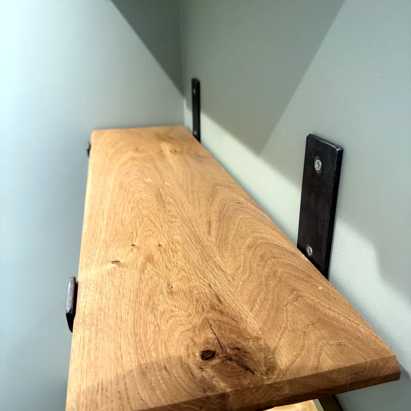 An oak shelf on black steel brackets